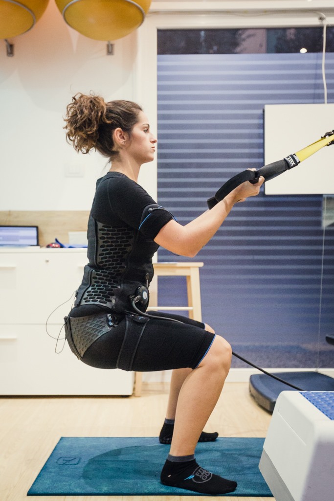 ragazza che esegue squat con trx e ems
